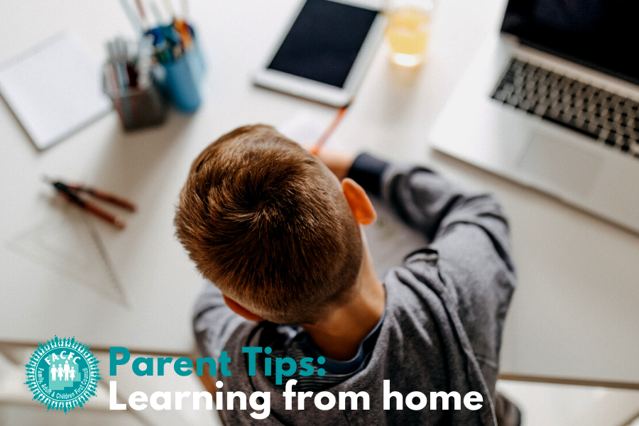 parent tip: learning from home boy at desk with laptop and phone writing